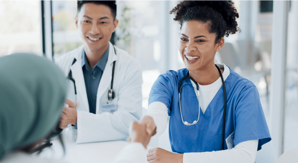 Smiling nurse shaking hands with a patient, doctor sitting beside her.